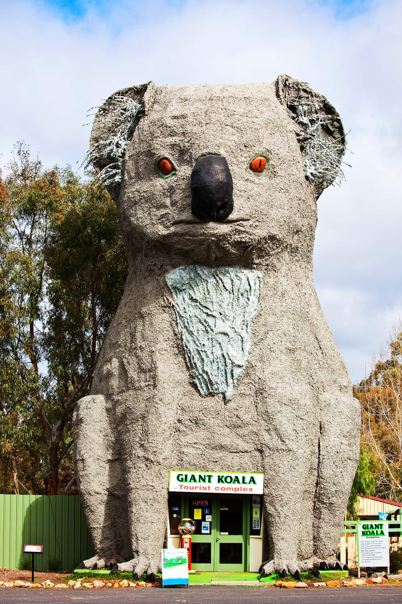 A statue of a giant koala flanked by tall trees.