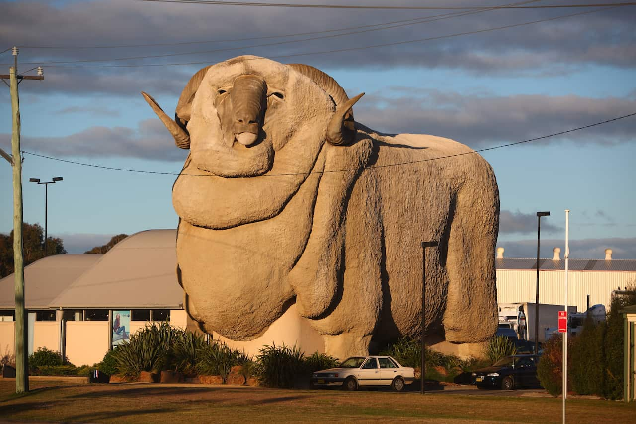 A giant concrete statue of a merino next to a house.