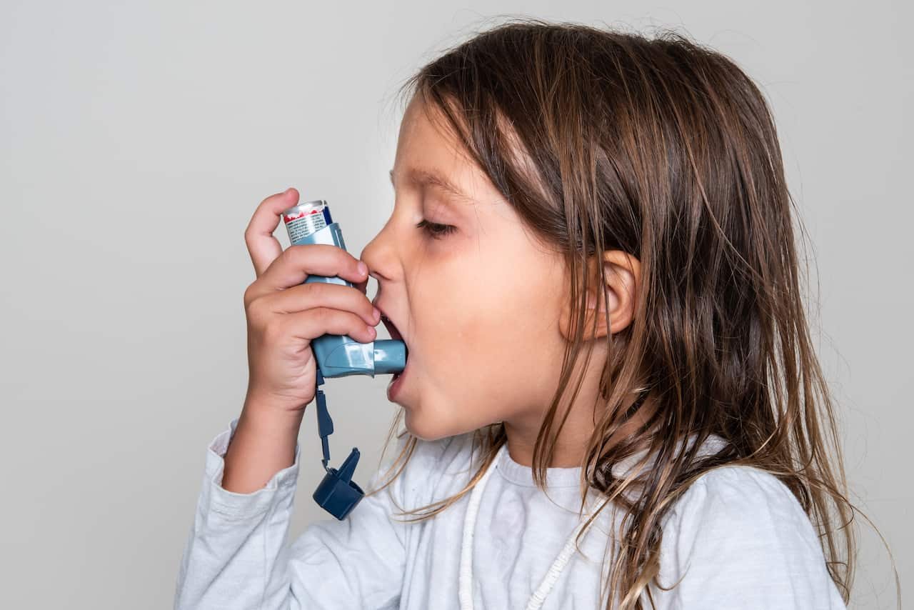 Little girl taking her asthma medicine