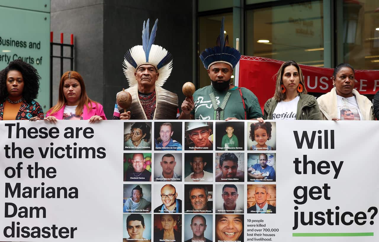 A group of people holding up a banner that reads: "These are the victims of the Mariana Dam disaster. Will they get justice?"