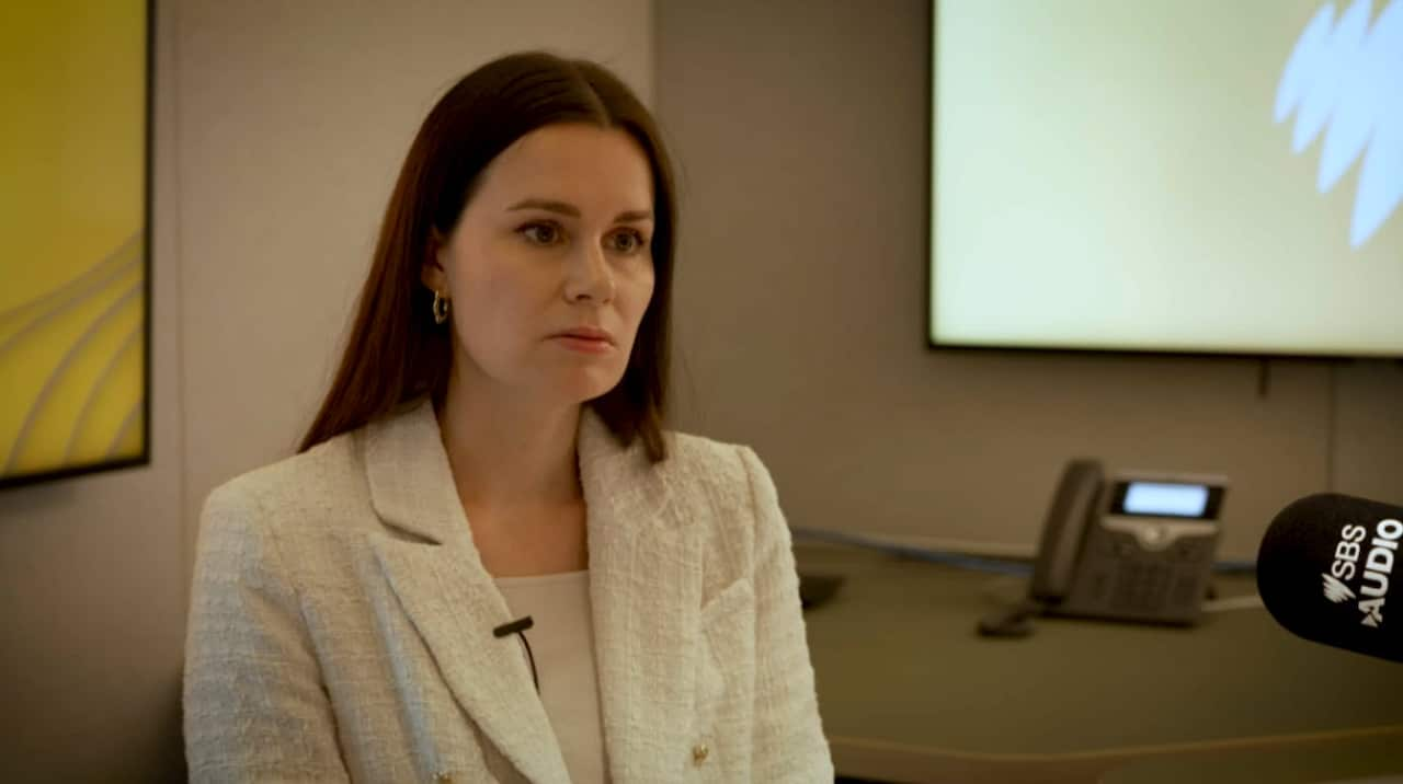 A woman in a white blazer is being interviewed. 