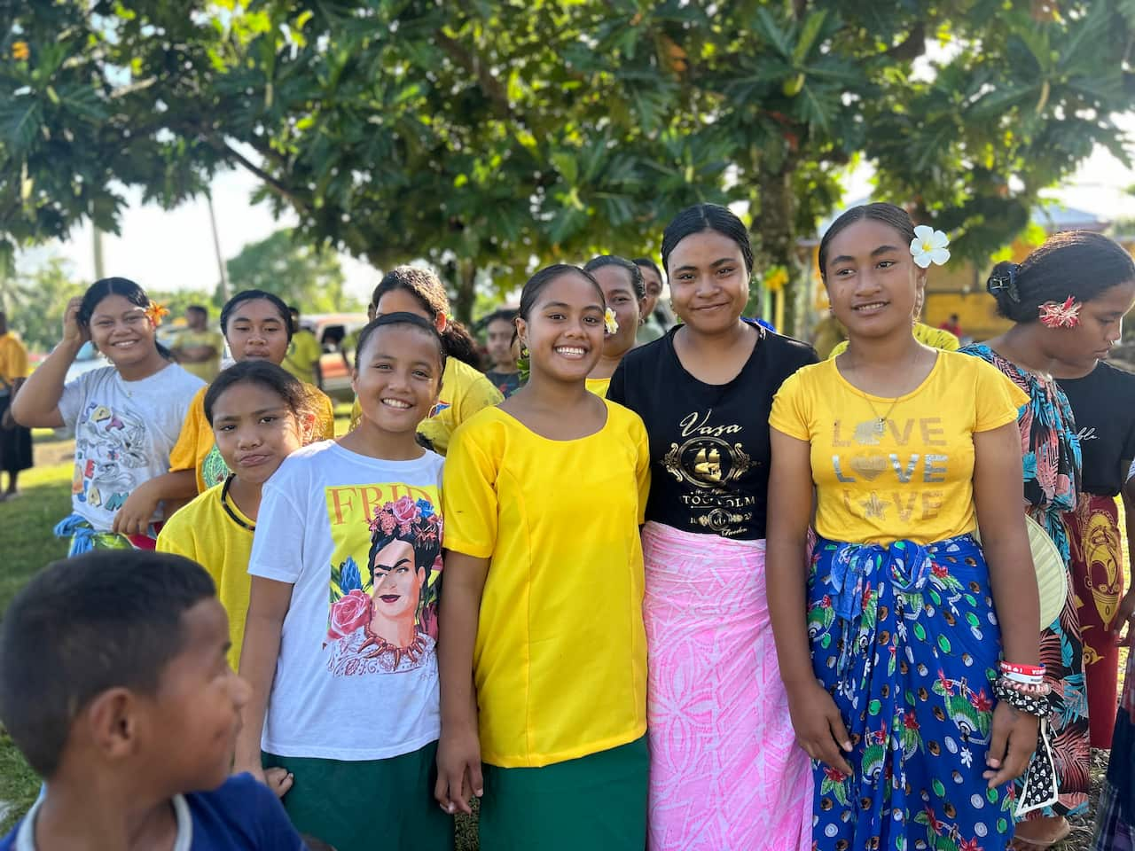 A group of girls smile as they stand outside while posing for a photo.