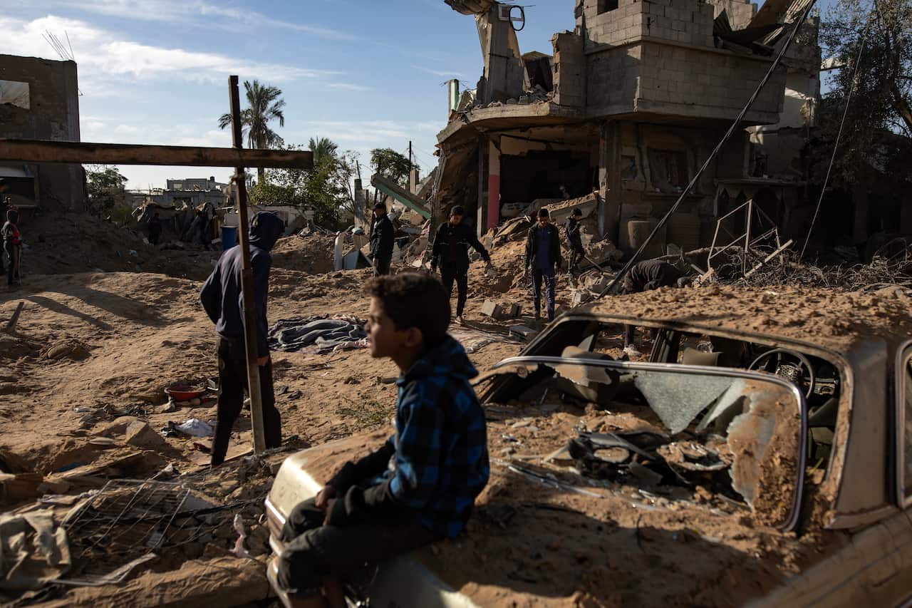 Palestinians inspect the remains of destroyed buildings in Khan Younis