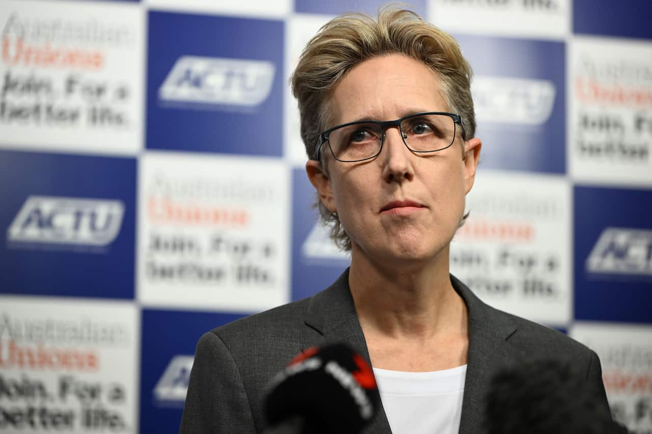 Woman diverts gaze while standing in front of a microphone.