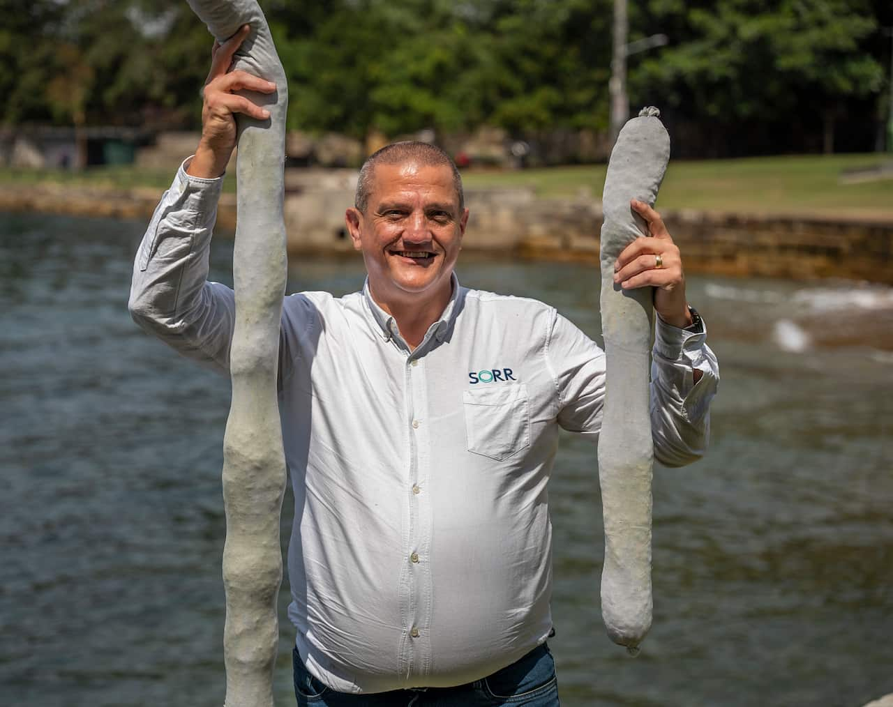 A man is smiling as he holds up two sponges.