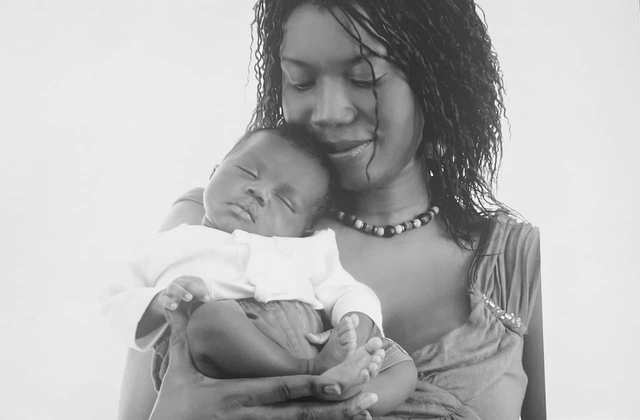 A black and white image of a woman holding a newborn baby.