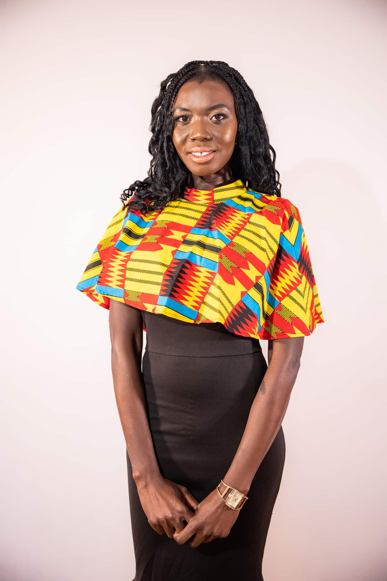 A woman in a black dress and colourful shawl smiles at the camera.