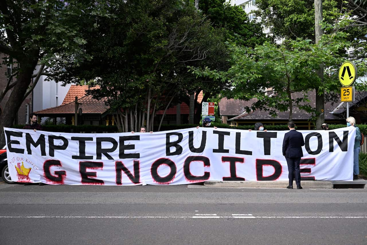 People hold up a big banner reading, "Empire built on genocide."