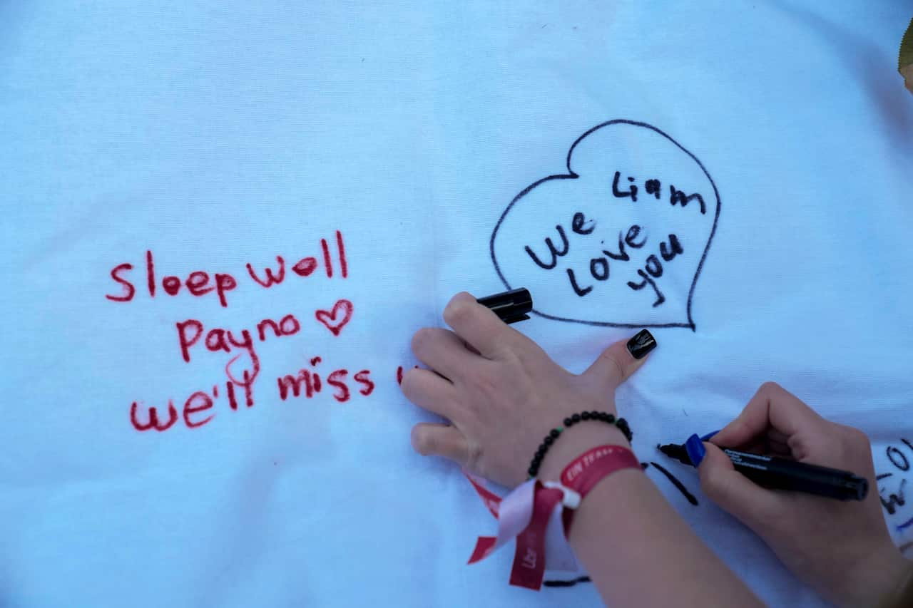 A fan is writing a message on a white sheet. 