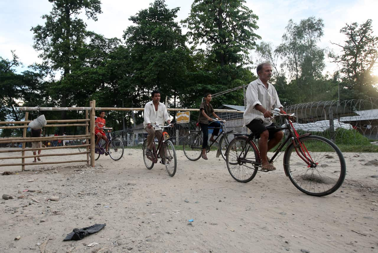 Bhutanese refugees cycle past a police c