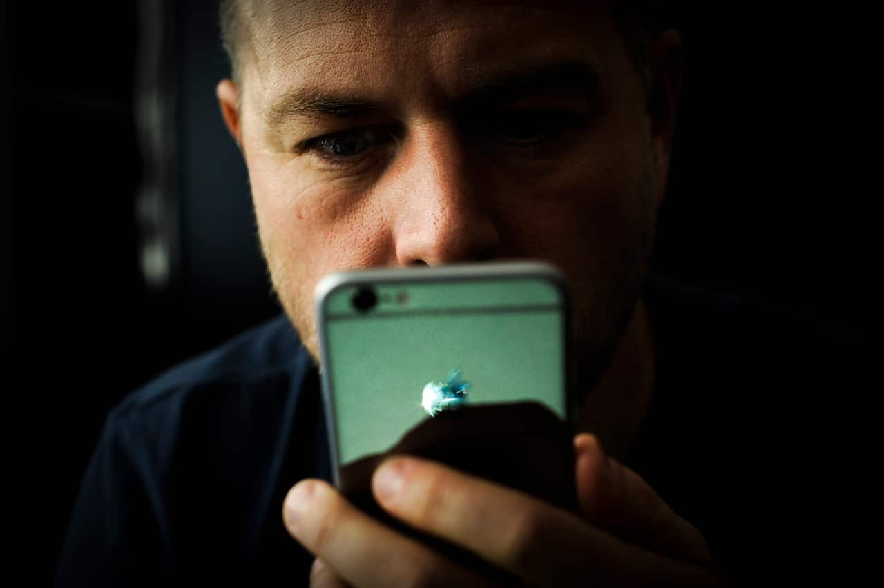 A young man holding a phone and looking at it. 