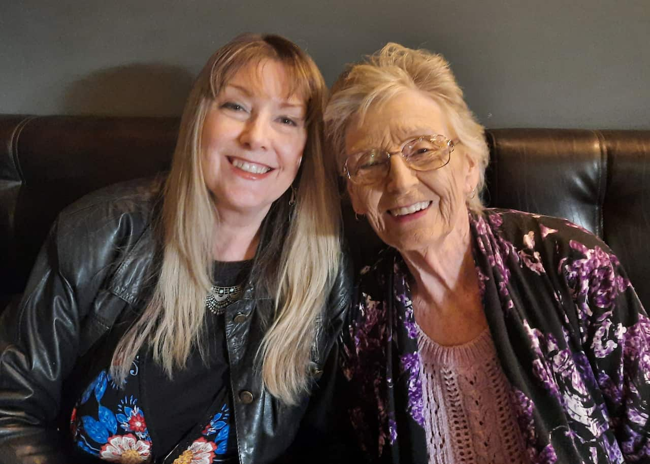 Two women sitting down smiling.