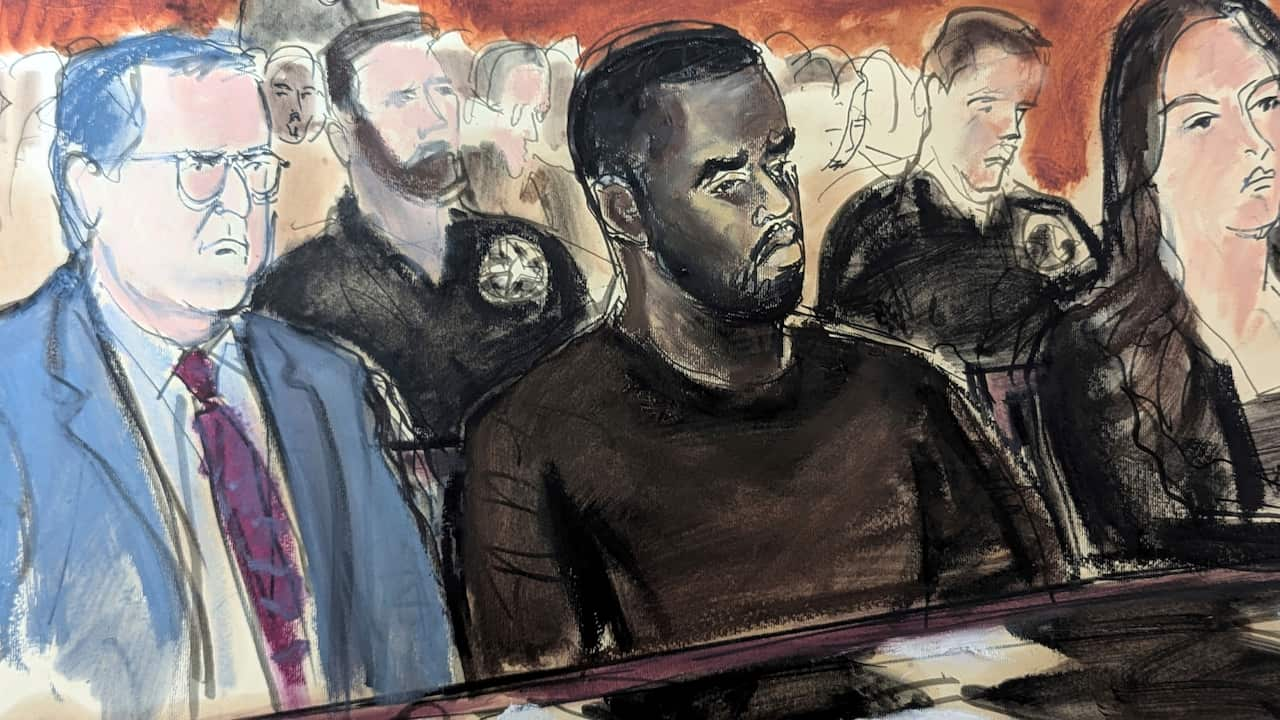 An artist's sketch depicts a man in a blue suit and tie sitting next to another man in a black round-neck t-shirt, with a woman beside them and abstract figures of people sitting behind them in a courtroom.