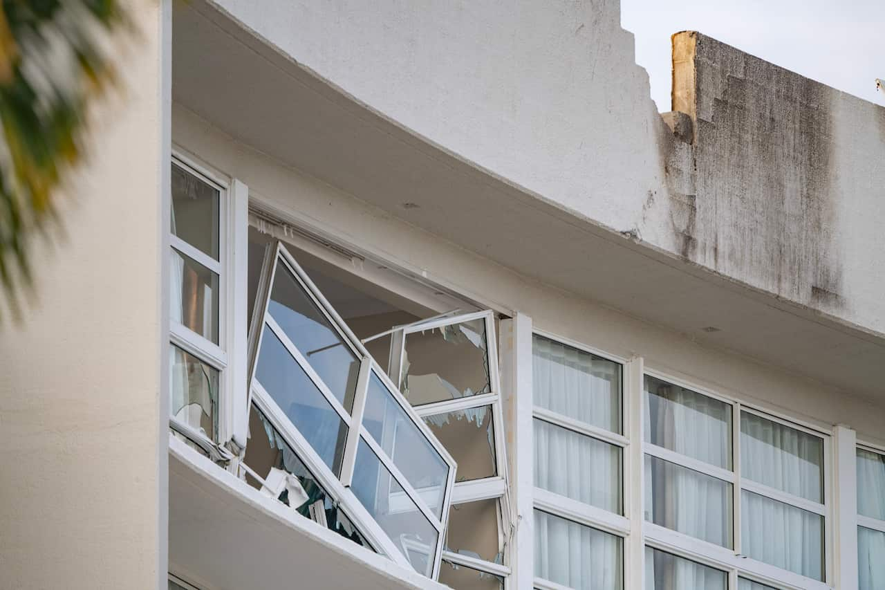 A white building with smashed windows.