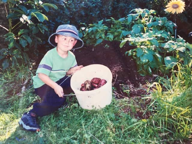 a young boy holding a bucket of potatoes 