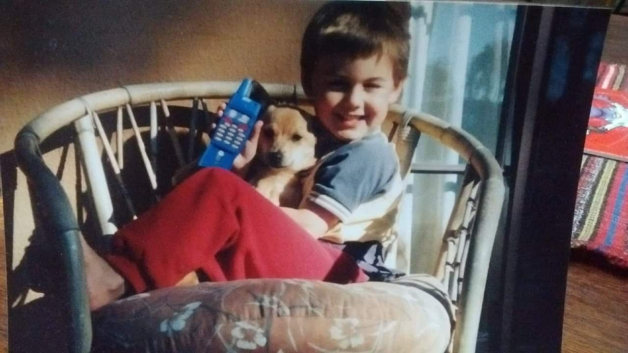 A little boy holding a small dog 