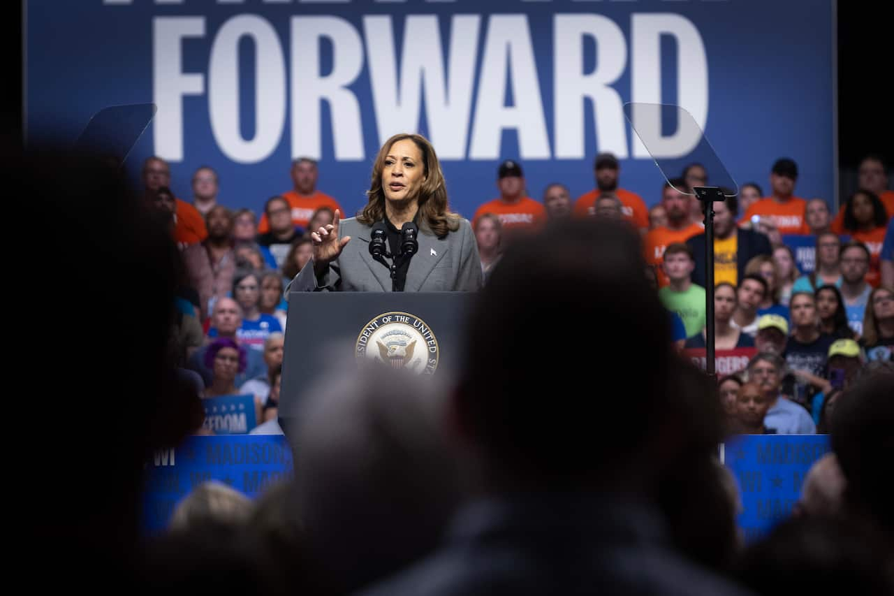 A woman stands at a podium in front of a large crowd.