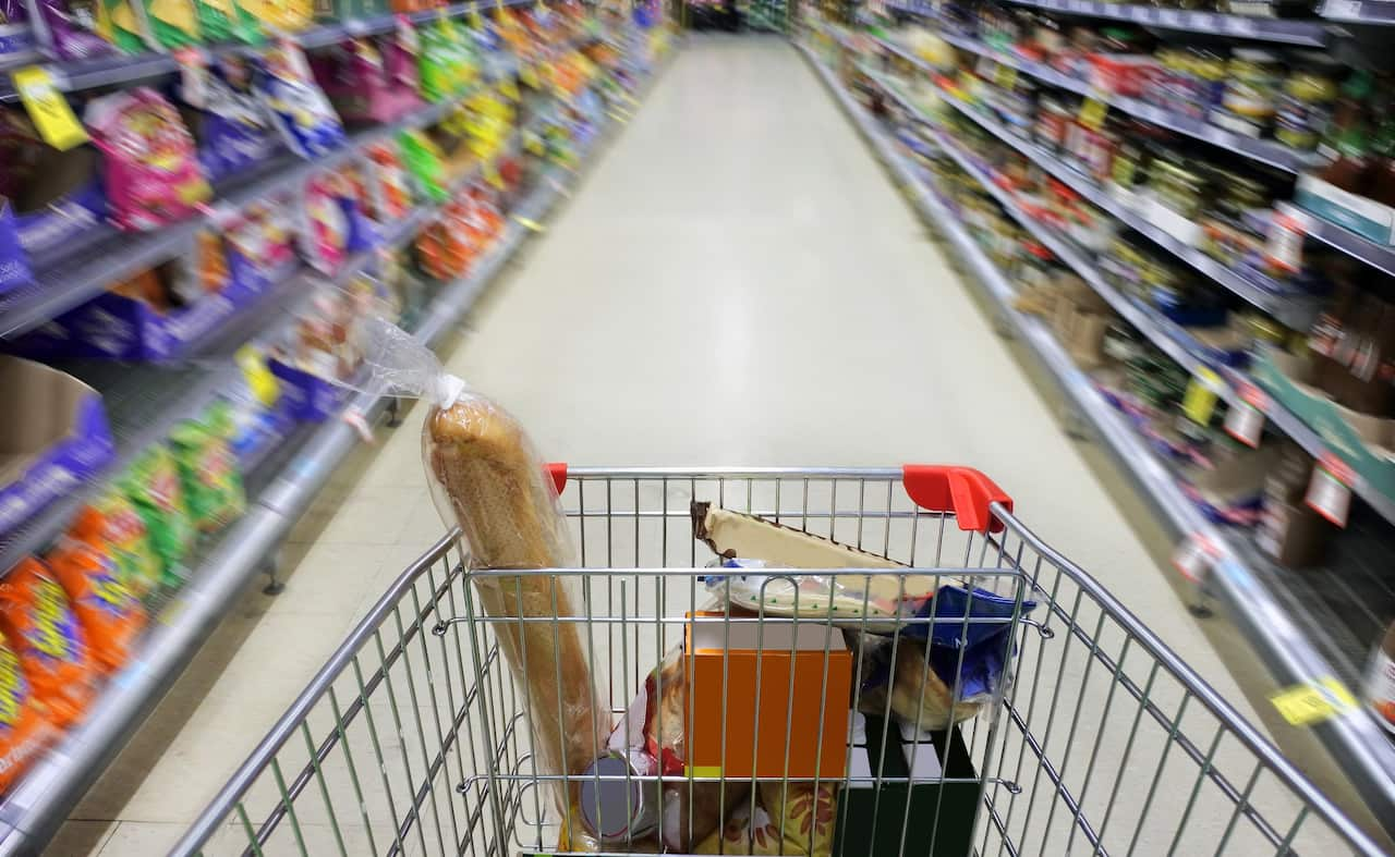 The view from the perspective of someone pushing a trolley down an aisle at a supermarket.