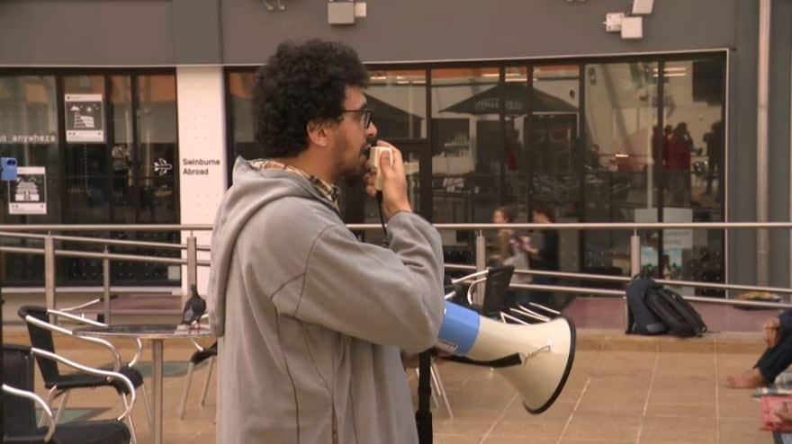 A man standing outside and speaking into a megaphone.