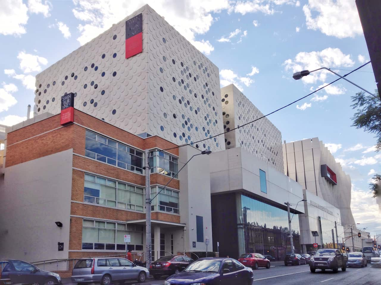 Cars driving by on a road outside Swinburne University.