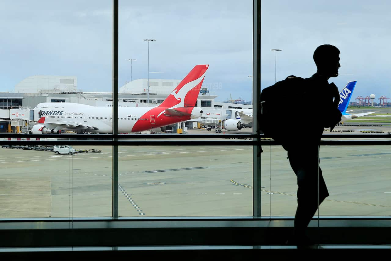 A man walking past a window at an airport. There are planes parked outside.