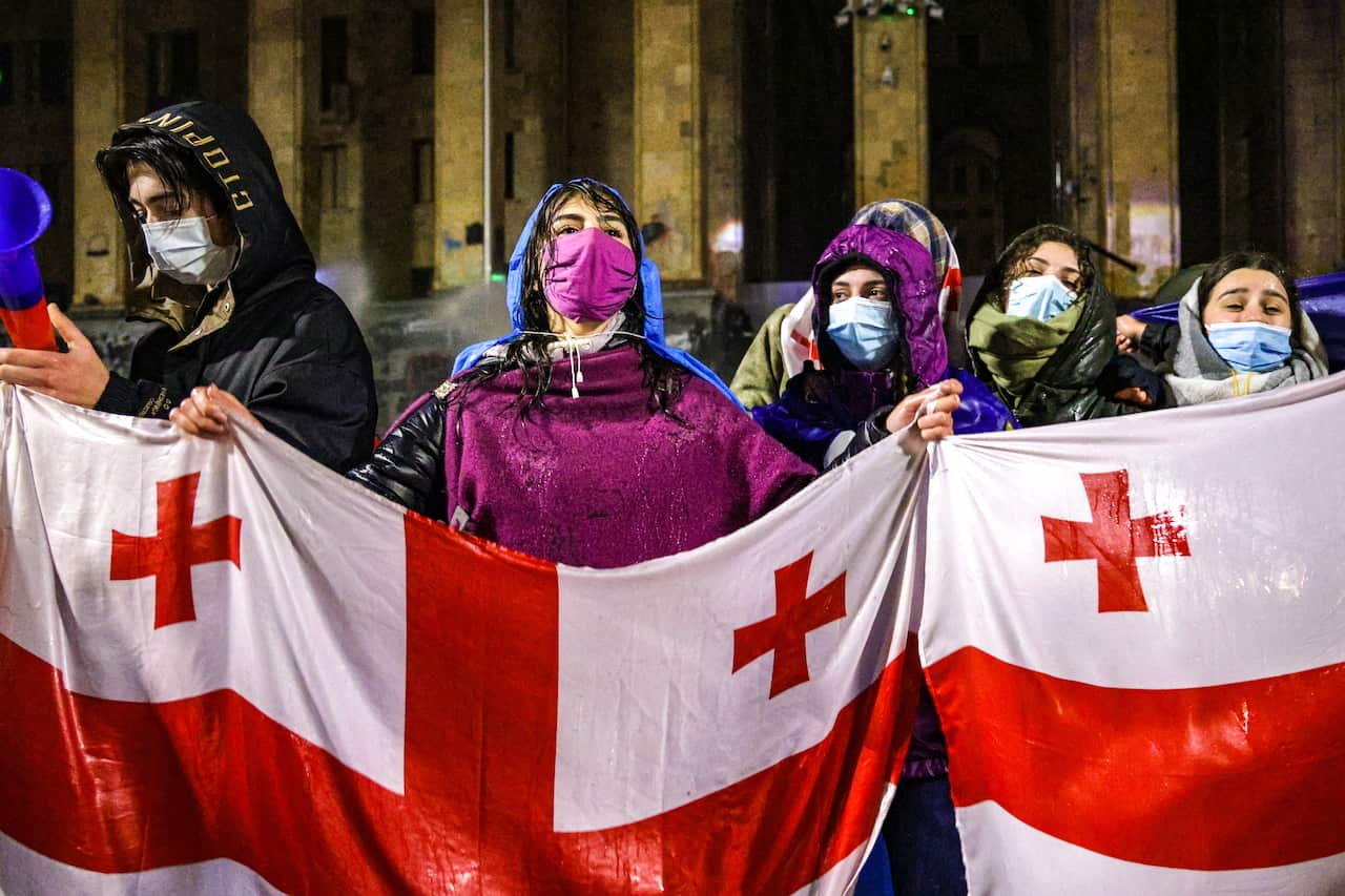 Protesters holding a flag outside Tbilisi Parliament Building