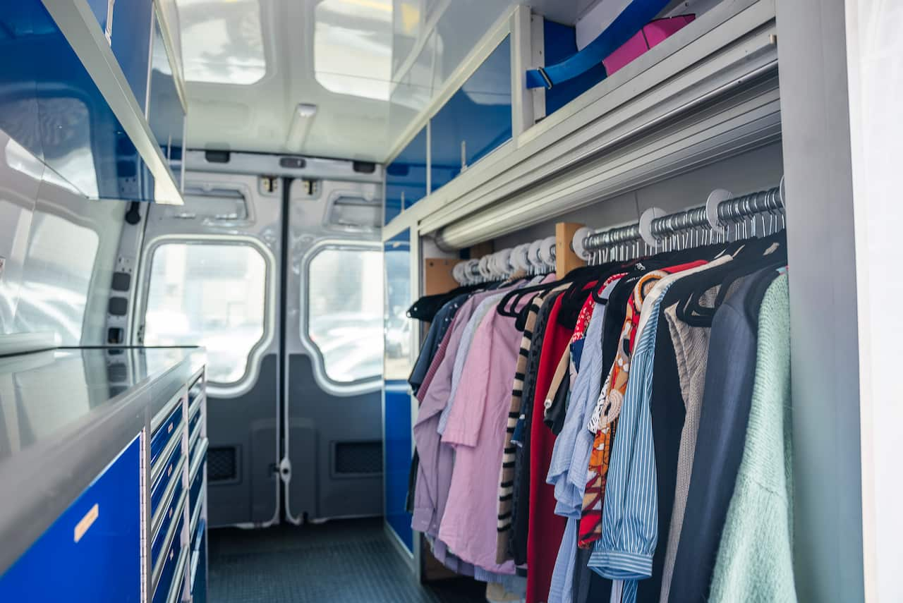 The interior of a van with drawers and hanging clothes.