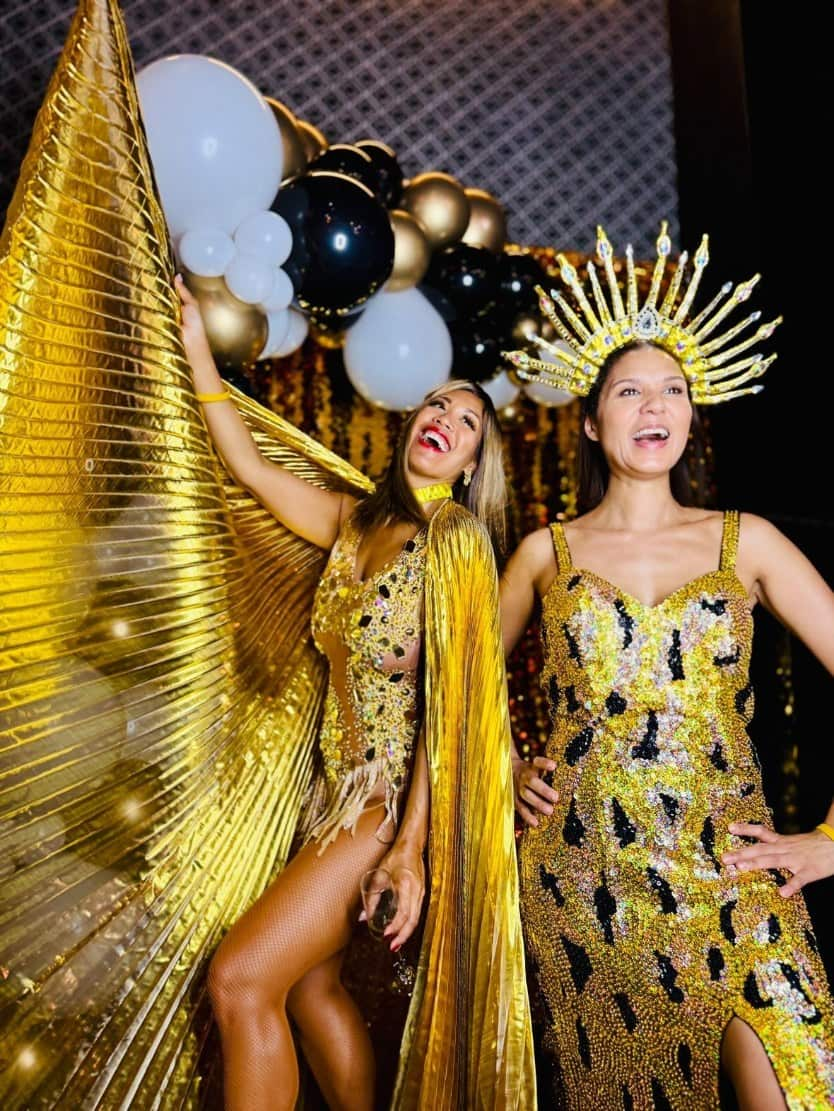 Two women dressed in sparkly gold outfits pose