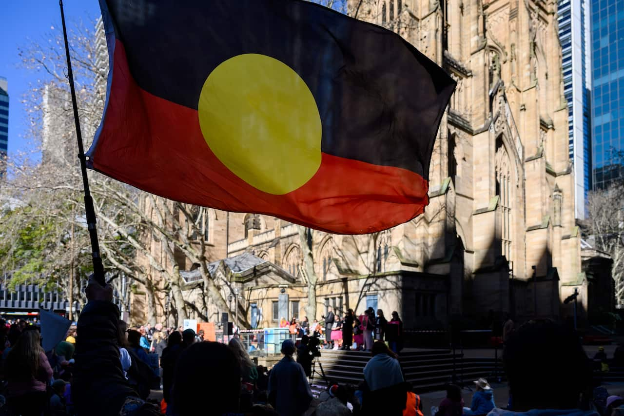 An Aboriginal flag being waved at a rally against domestic violence