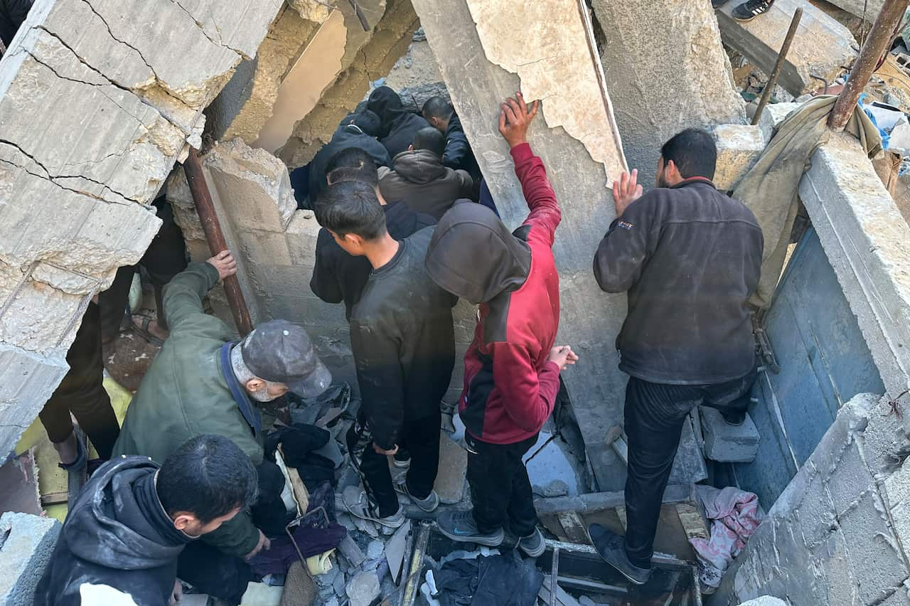 People searching through the rubble of a damaged building.