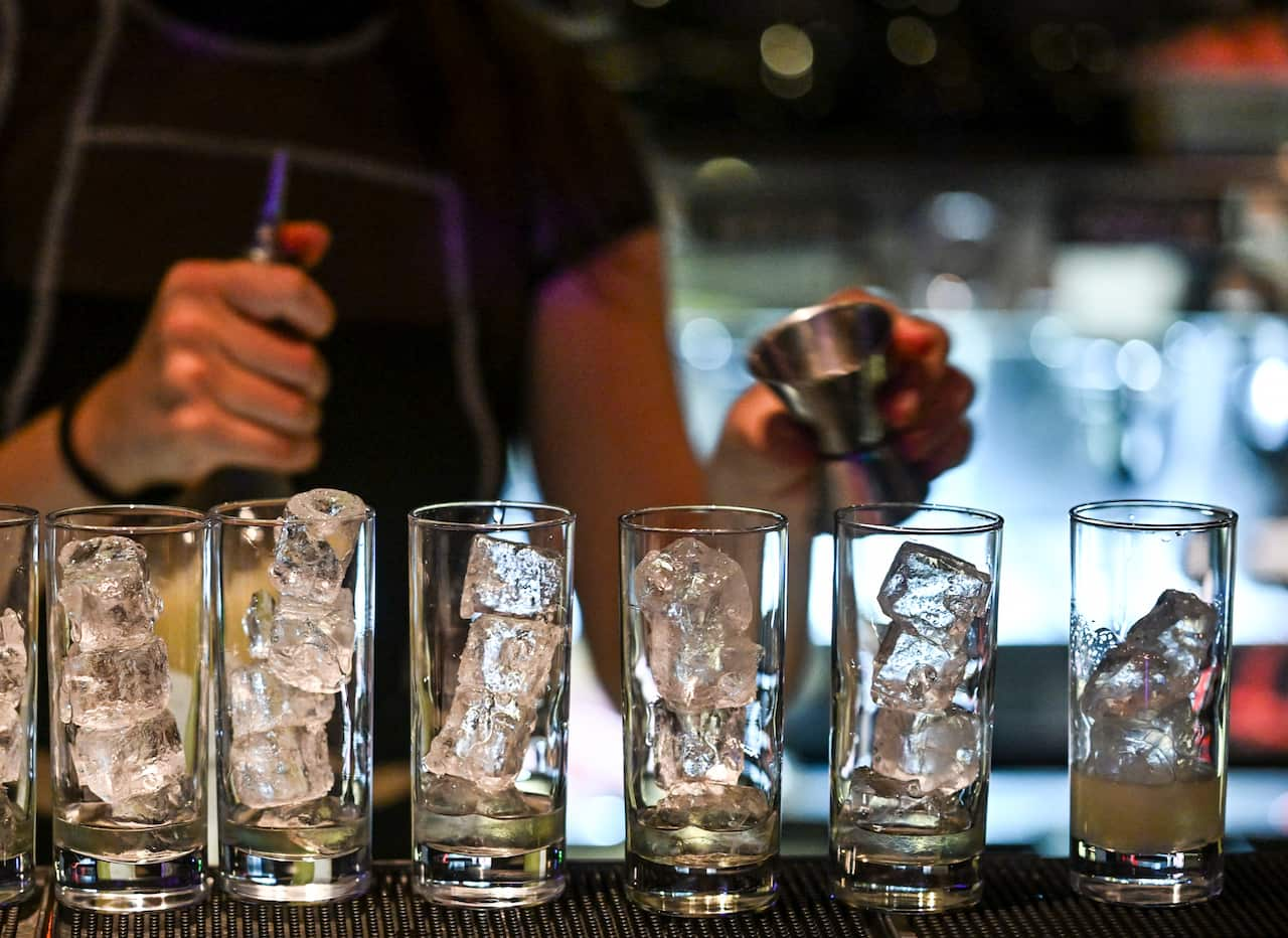 A row of glasses with ice in them on a bar.