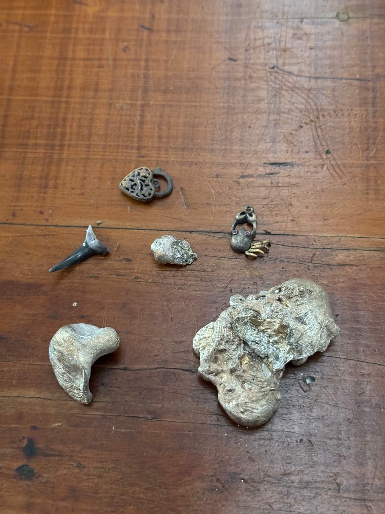 Pieces of melted jewellery lying on a wooden surface.