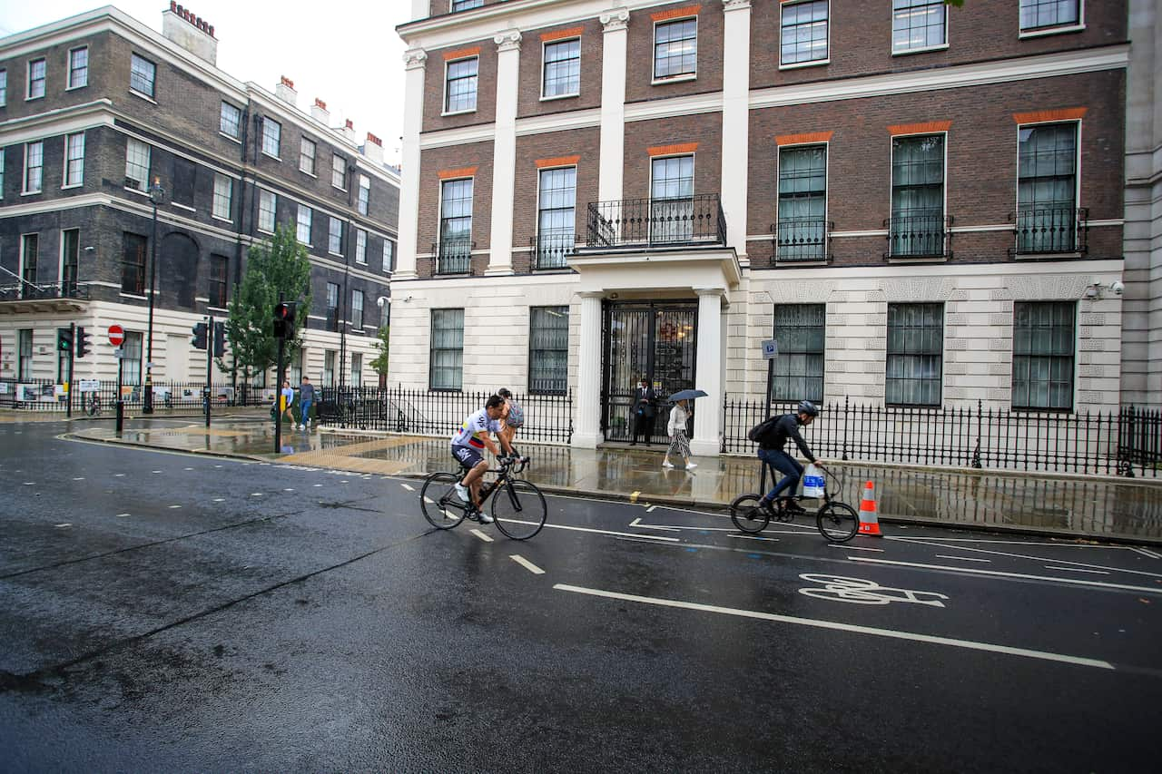 The exterior of a large building. People are cycling on the road out the front.