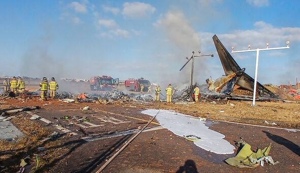 The tail section of a Jeju Air Boeing 737-800 series aircraft is seen beside rescue personnel 