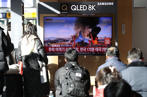 People watch the news regarding the plane crash at Seoul station