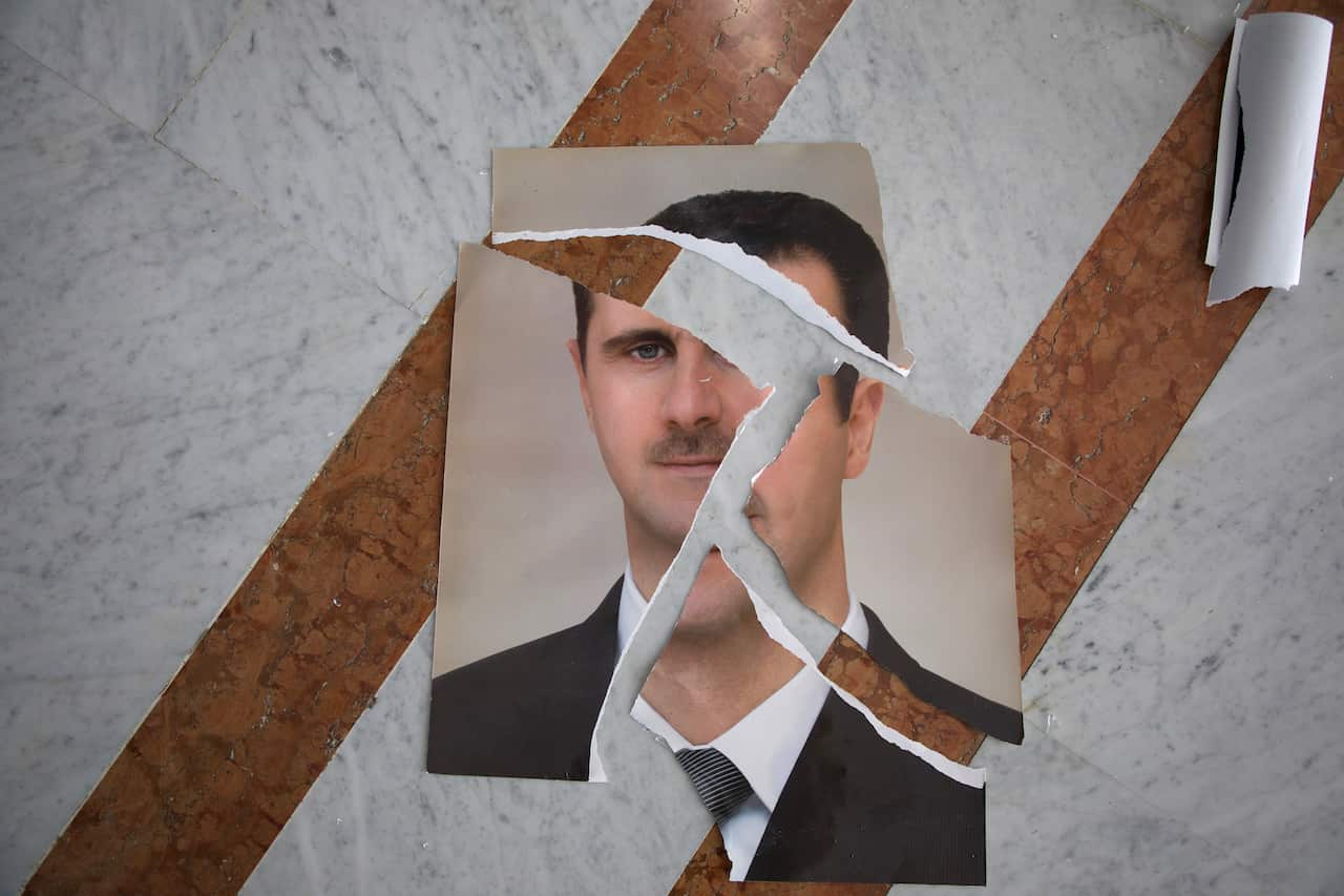 A torn portrait of a man wearing a suit is arranged on a marble floor.