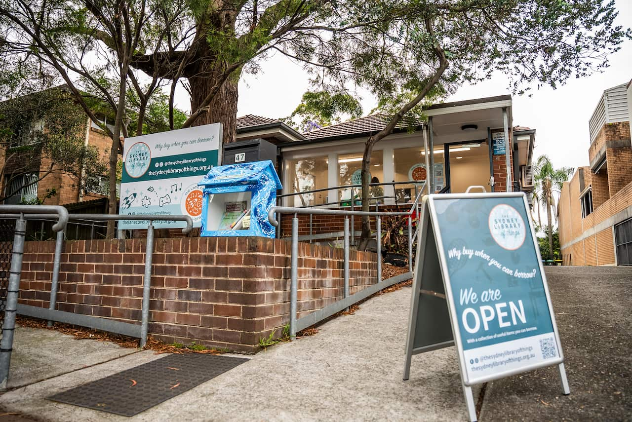 A small brick cottage with an easel sign at the front reading We are Open