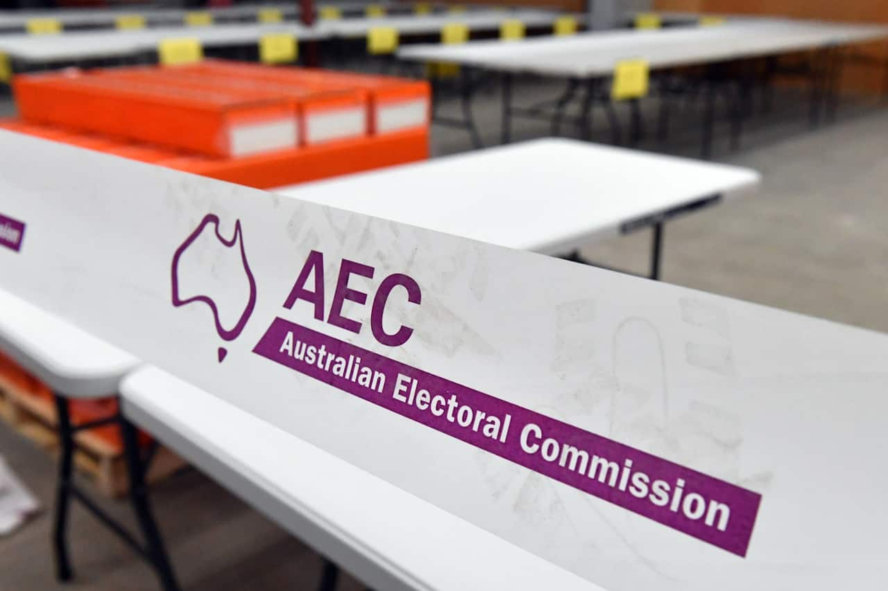 A white banner with the words 'AEC Australian Election Commission' written on it in purple ink.