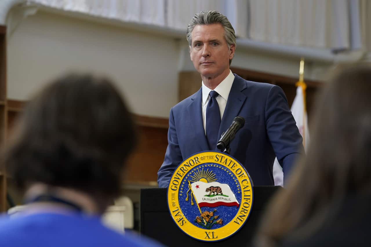 A man in a blue suit stands behind a podium addressing a crowd