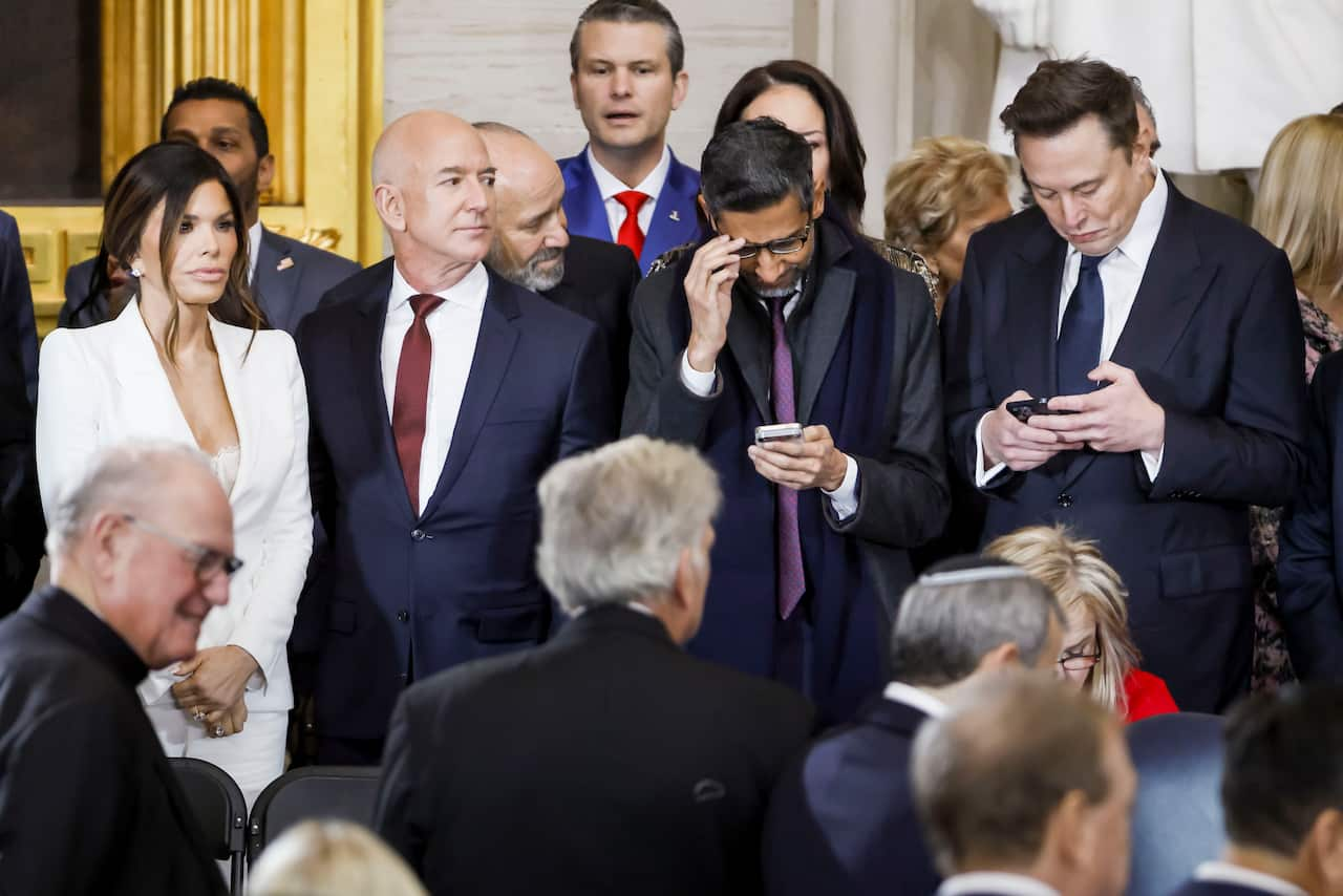 People in business attire are standing, with some looking at mobile phones.