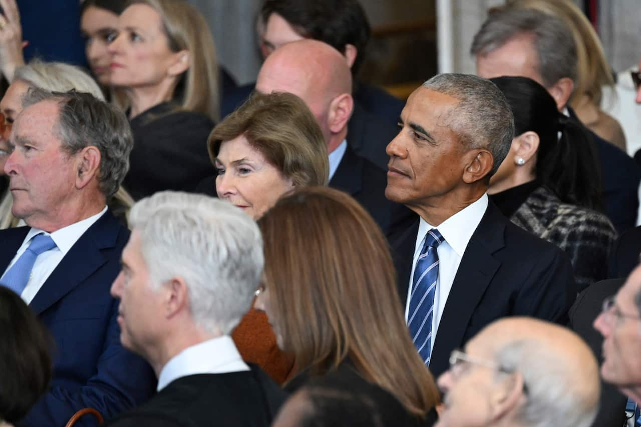 A group of people look forward as they are seated in a room. 