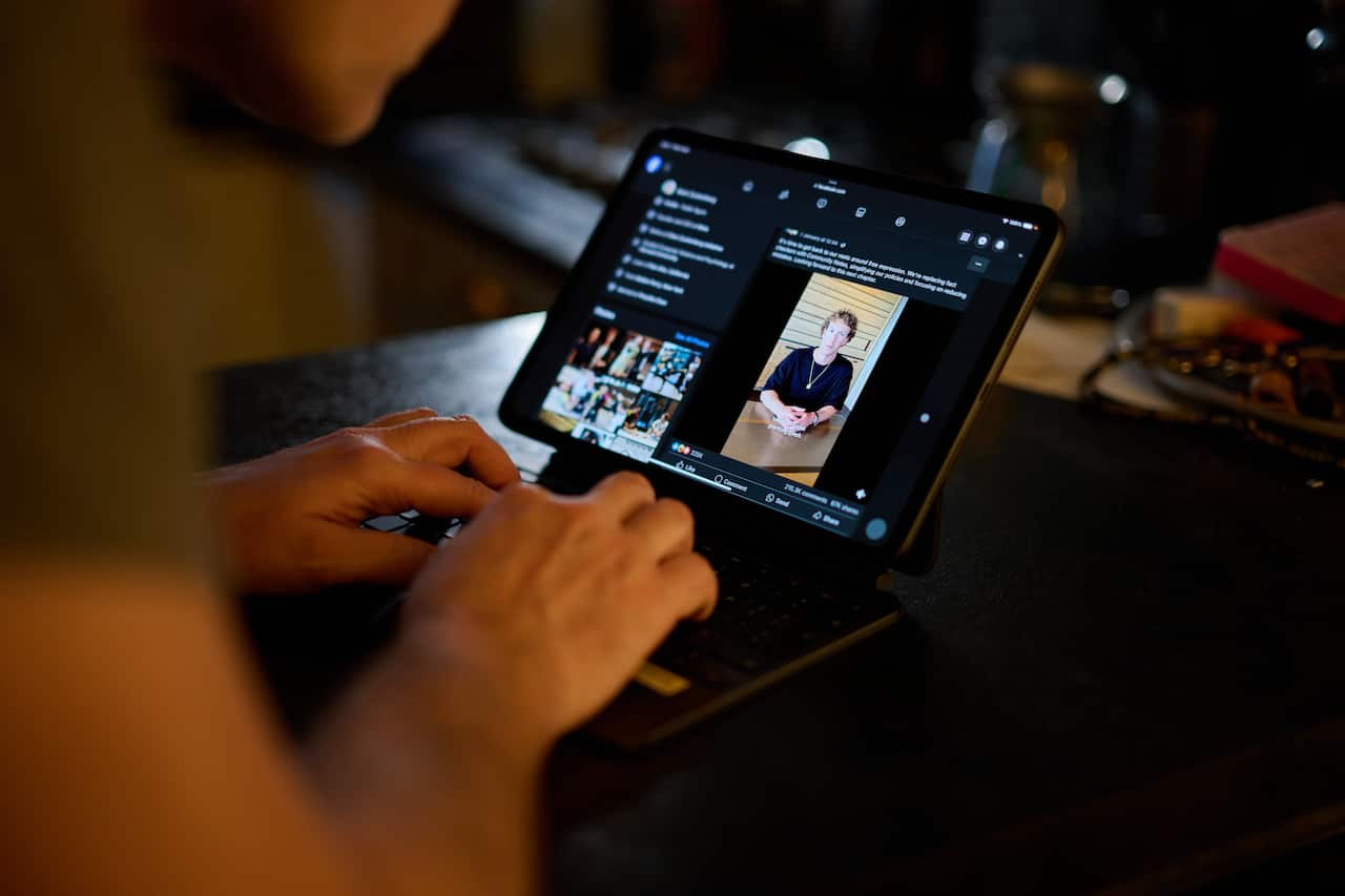 A person watching a video of Mark Zuckerberg on a laptop.