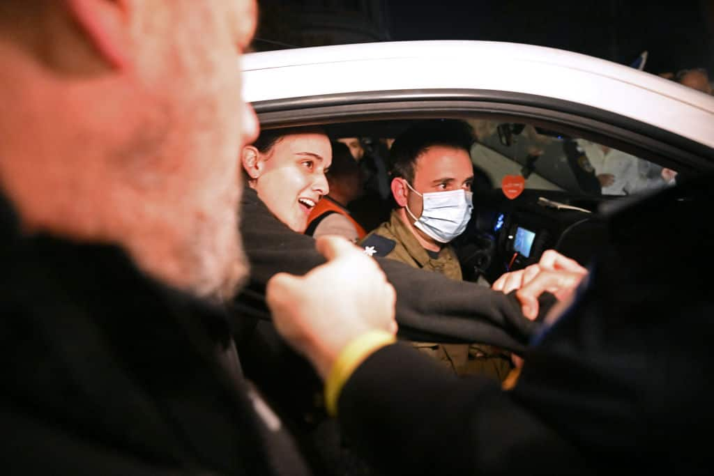 A woman arrives in a car, surrounded by cameras. 