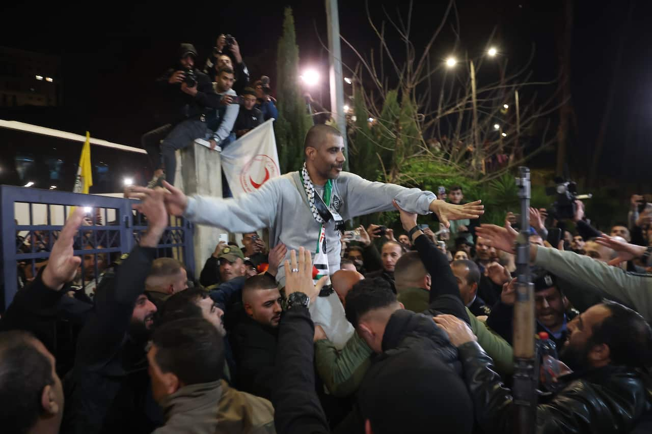 A man is being carried on shoulders while shaking hands with members of the crowd.