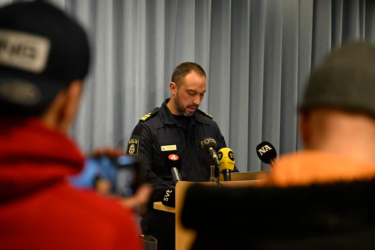 A policeman speaks into microphones at a press conference. 