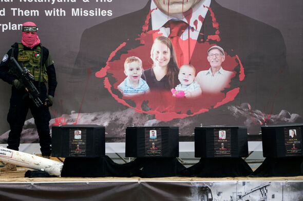 A Hamas militant stands over the coffins which were supposed to contain the bodies 