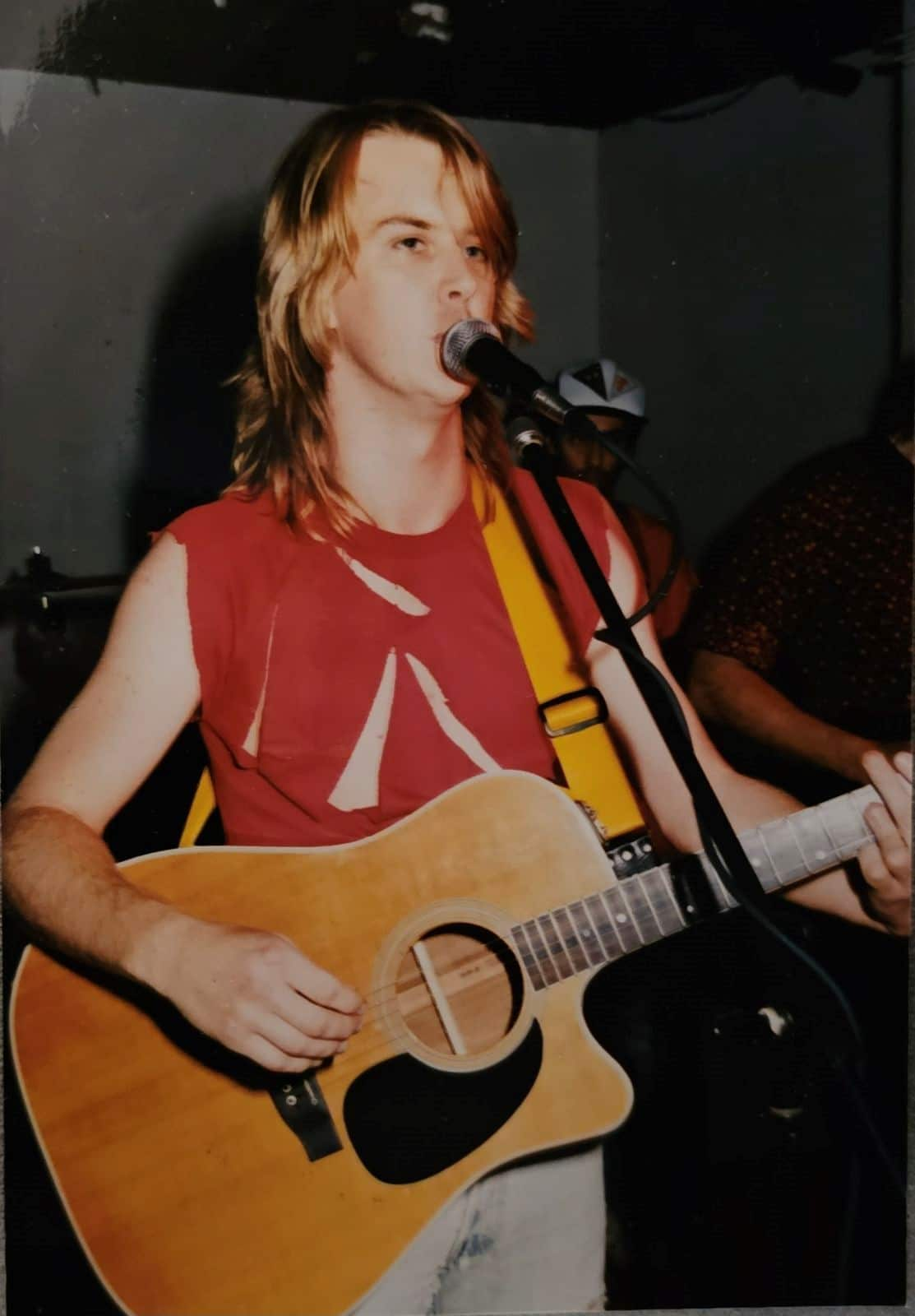 A teenage boy plays guitar and sings into the microphone.