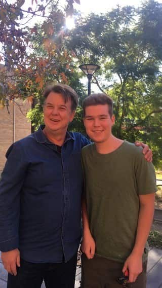 A father and his teenage son smile together for the camera.