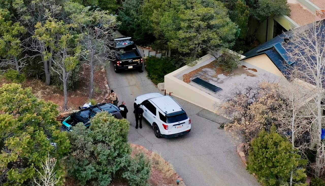 Cars outside a house flanked by trees.