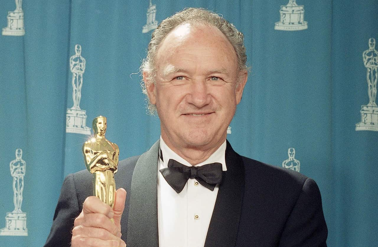 A man in a tuxedo holding up an Academy Award.